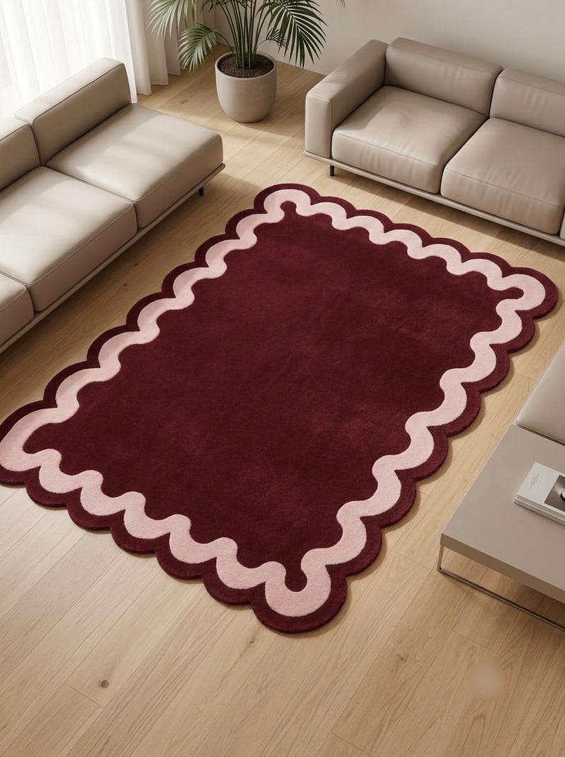 Hand tufted burgundy and pink scalloped area rug with a modern wavy border design, contemporary statement rug for living room or bedroom decor