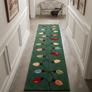 Peut inclure: Un long tapis de couloir rectangulaire de couleur vert forêt profond. Le tapis présente un motif central de cordon noir sinueux décoré de lumières de Noël colorées en forme d'ampoule dans des tons rouge, jaune, orange, bleu clair et vert lime.