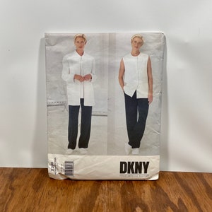 May include: A DKNY sewing pattern featuring a woman in a white jacket and black pants, and a sleeveless top with black pants. The pattern is on a cream-colored background with the DKNY logo in the bottom right corner.
