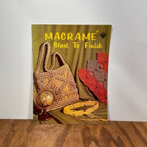 May include: A vintage book cover titled "MACRAMÉ Start To Finish" featuring macramé projects. The cover displays a macramé tote bag, a decorative square, and a yellow belt. A small globe sits in front of the bag.