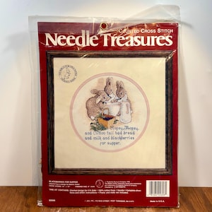 May include: A counted cross stitch kit titled "Needle Treasures" featuring a framed design of three bunnies preparing a meal. The design includes the text "But Hopsy, Mopsy, and Cotton-tail had bread and milk and blackberries for supper."