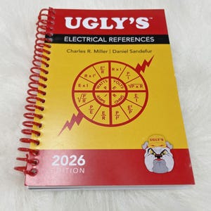 May include: A spiral-bound reference book titled Ugly's Electrical References 2026 Edition. The cover is yellow and red with a central circular diagram of electrical formulas and a cartoon bulldog wearing a yellow hat in the bottom right corner.