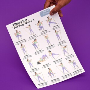 May include: A white Pilates Bar Full Body Workout chart held by a hand. The chart features illustrated exercises with instructions, including squats, lunges, and presses. The text indicates a 15-20 minute workout.