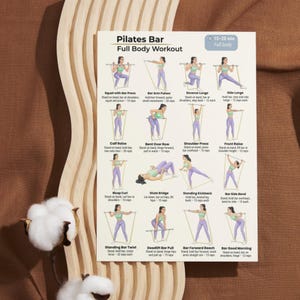 May include: A Pilates Bar Full Body Workout chart with illustrated exercises. The chart includes exercises like squats, lunges, and presses, with instructions and rep counts. The background is a light brown color with a cotton flower on the left.