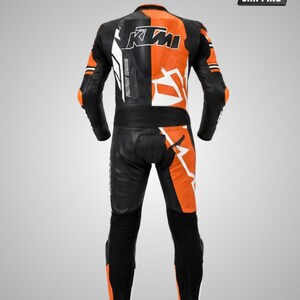 May include: A black and orange motorcycle racing suit featuring the text KTM on the upper back. The suit is constructed with leather panels, integrated protective padding at the elbows and knees, and a split color design across the torso and legs.