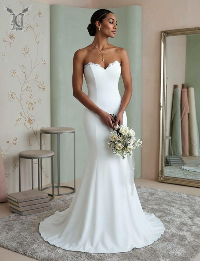 Elegant minimalist strapless mermaid wedding dress in satin fabric with delicate lace neckline, fitted bridal gown with modern boho style and long train.