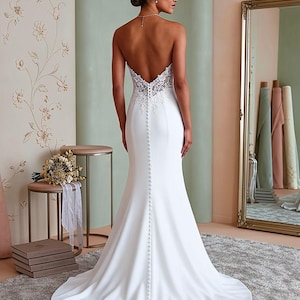 Back view of minimalist satin mermaid bridal gown featuring strapless design, sleek fitted silhouette, elegant train, and timeless modern wedding style.