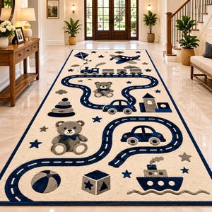 May include: A rectangular beige rug with a navy blue border and a playful design. The rug features a road pattern with toy cars, a train, a ship, a plane, a kite, stars, a building, a ball, and teddy bears. The rug is designed for a child's room.