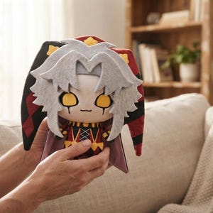May include: A plush toy featuring a character with spiky light grey hair, large yellow eyes, and a jester-style hat in black and red with yellow star accents. The character wears a black and red outfit with a crisscross pattern on the chest.