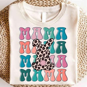 May include: Cream-colored t-shirt with the word "MAMA" repeated four times in a retro font. A leopard print bunny is centered on the shirt. The letters are in pink, teal, and coral.