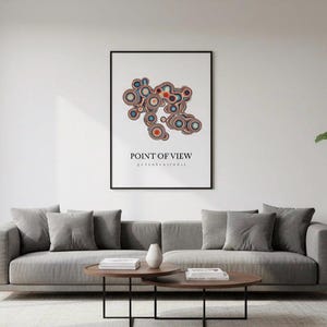Könnte beinhalten: Ein Wohnzimmer mit einem grauen Sofa, Kissen und einem gerahmten Kunstwerk. Das Kunstwerk zeigt ein abstraktes Design und den Text "POINT OF VIEW". Ein runder Couchtisch und eine Topfpflanze vervollständigen die Szene.