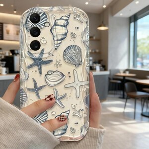 May include: Clear phone case featuring a pattern of blue and white seashells and starfish. The design includes various shell shapes and starfish on a light background. The case has a glossy finish and a camera cutout.