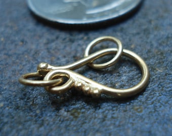 May include: Gold-toned metal clasp with a loop and a hook. The clasp is designed with a decorative swirl.