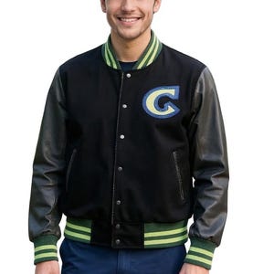 May include: Black varsity jacket with leather sleeves, featuring a large "G" patch in blue and yellow. The jacket has green and yellow striped accents on the collar, cuffs, and hem. A classic, sporty outerwear piece.