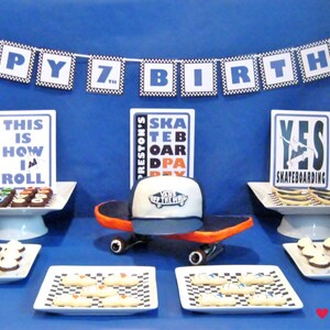 Puede incluir: Una mesa de postres para una fiesta de cumplea&ntilde;os con fondo azul y una pancarta que dice "Feliz 7&ordm; cumplea&ntilde;os". Hay tres soportes para pasteles blancos con varios postres, incluyendo cupcakes, galletas y brownies. El soporte para pasteles del centro tiene una patineta con un sombrero Vans en la parte superior. Tambi&eacute;n hay tres letreros con el texto "As&iacute; es como ruedo", "Fiesta de patineta de Preston" y "S&iacute; al patinaje".
