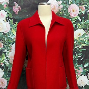 May include: A vibrant red jacket with a classic collar and two front pockets. The jacket is displayed on a mannequin, showcasing its tailored fit and clean lines. The long sleeves and open front design create a polished look.