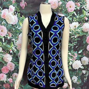 May include: A black sleeveless vest with a geometric pattern in shades of blue and purple. The vest has a V-neck and button closure.