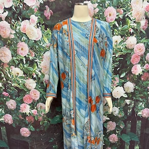 May include: A long blue and orange patterned dress with a matching long-sleeved jacket. The dress and jacket have a blue background with orange and white floral designs.