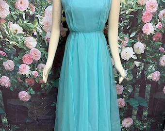 May include: A floor-length sleeveless dress in a solid turquoise color. The garment features a round neckline, a fitted bodice with a defined waistline, and a long, flowing skirt made of a lightweight, semi-sheer fabric that drapes to the floor.