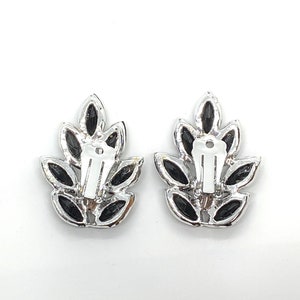 May include: A pair of silver tone clip-on earrings with black leaf-shaped stones.