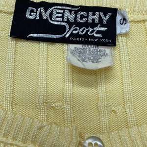 May include: A yellow ribbed knit cardigan with a button closure and a black label that reads "Givenchy Sport Paris - New York".