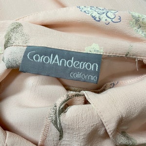 May include: A close-up of a pink fabric with a floral print. The fabric has a label that reads "Carol Anderson California".