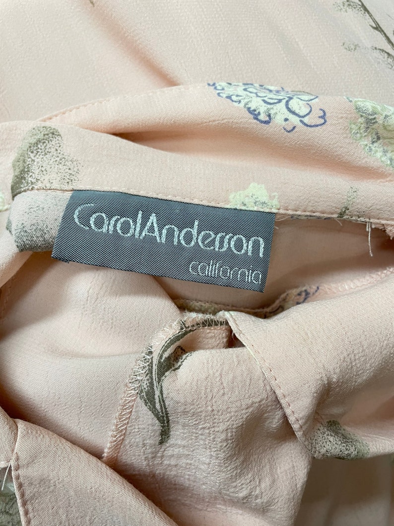 May include: A close-up of a pink fabric with a floral print. The fabric has a label that reads "Carol Anderson California".