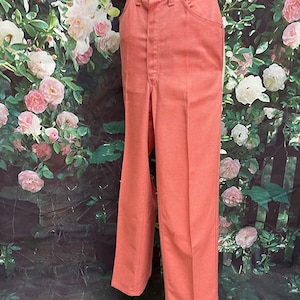 May include: A pair of wide-leg pants in a coral pink color. The pants have a high waist and a straight leg.