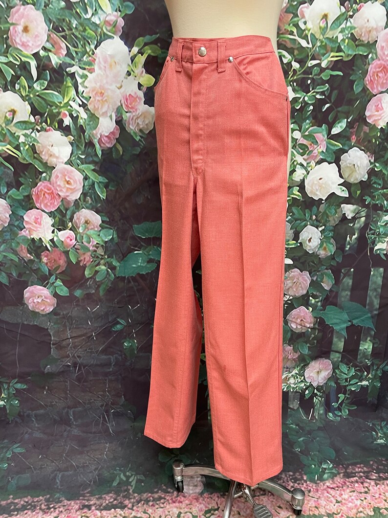 May include: A pair of wide-leg pants in a coral pink color. The pants have a high waist and a straight leg.