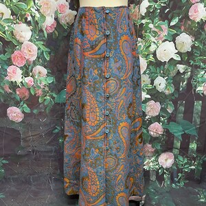 May include: A long blue skirt with a paisley pattern in shades of orange and brown. The skirt has a button-up front closure.
