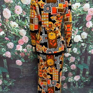 May include: A vintage two-piece suit with a geometric and floral pattern in shades of brown, orange, and black. The jacket has a collar and long sleeves. The skirt is long and has a straight silhouette.