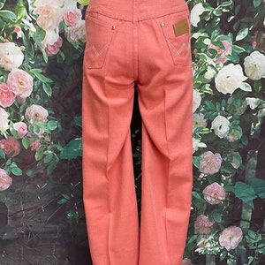 May include: A pair of light pink wide-leg jeans with a high waist and a classic five-pocket design. The jeans have a subtle texture and are made of a lightweight fabric.