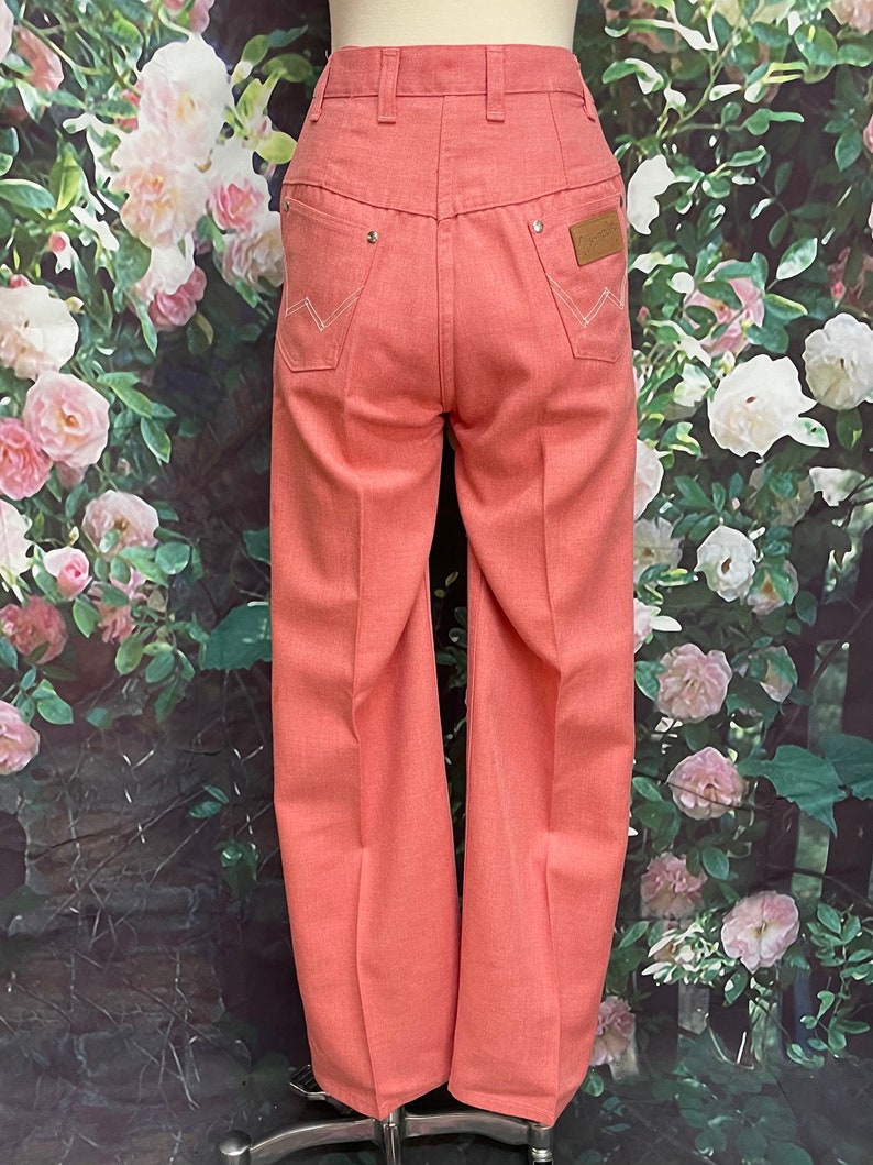 May include: A pair of light pink wide-leg jeans with a high waist and a classic five-pocket design. The jeans have a subtle texture and are made of a lightweight fabric.