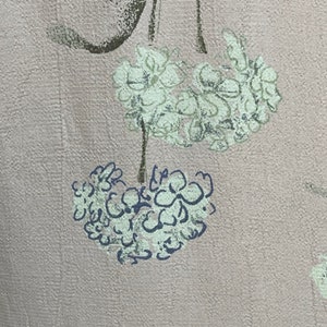 May include: A pale pink fabric with a floral pattern. The flowers are white with a light green outline and a dark blue center.