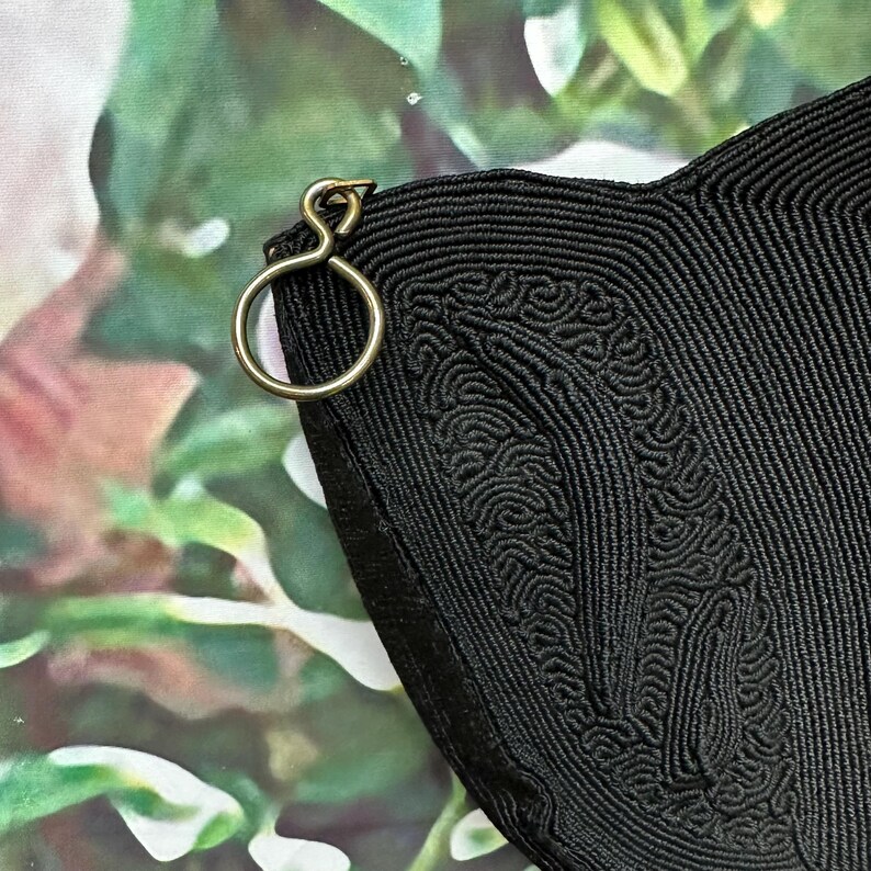 May include: Black woven bag with a gold metal clasp. The bag has a unique textured design.