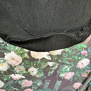 May include: Black knitted fabric with a textured surface. The fabric is folded in half and the edges are visible.