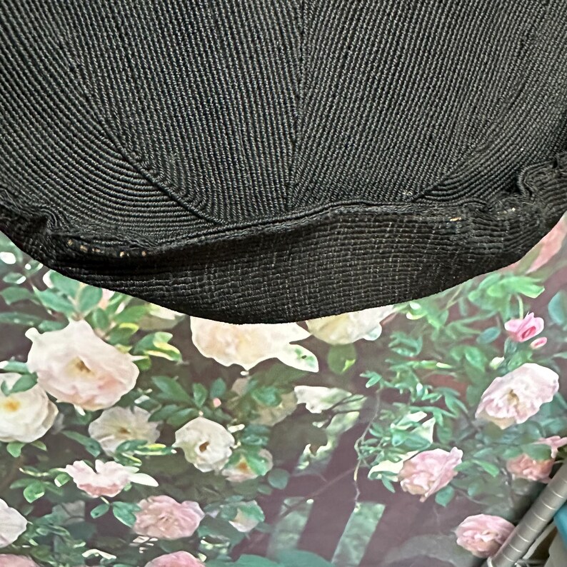 May include: Black knitted fabric with a textured surface. The fabric is folded in half and the edges are visible.