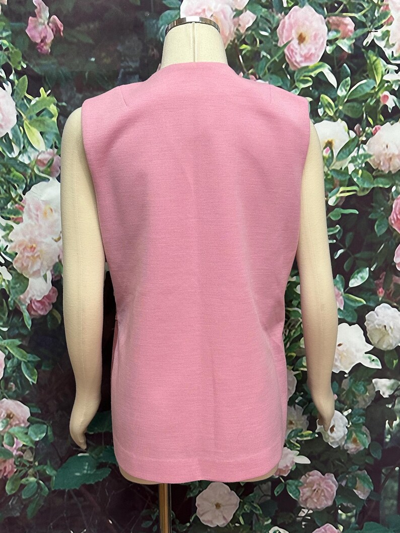 May include: A sleeveless pink vest with a V-neckline. The vest is made of a soft, textured fabric.