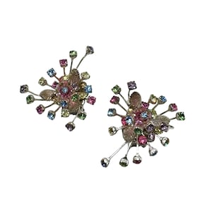 May include: A pair of silver earrings with a floral design. Each earring features a cluster of colourful square-cut gemstones in shades of pink, blue, green, and purple, with delicate leaf accents. The earrings are set against a white background.