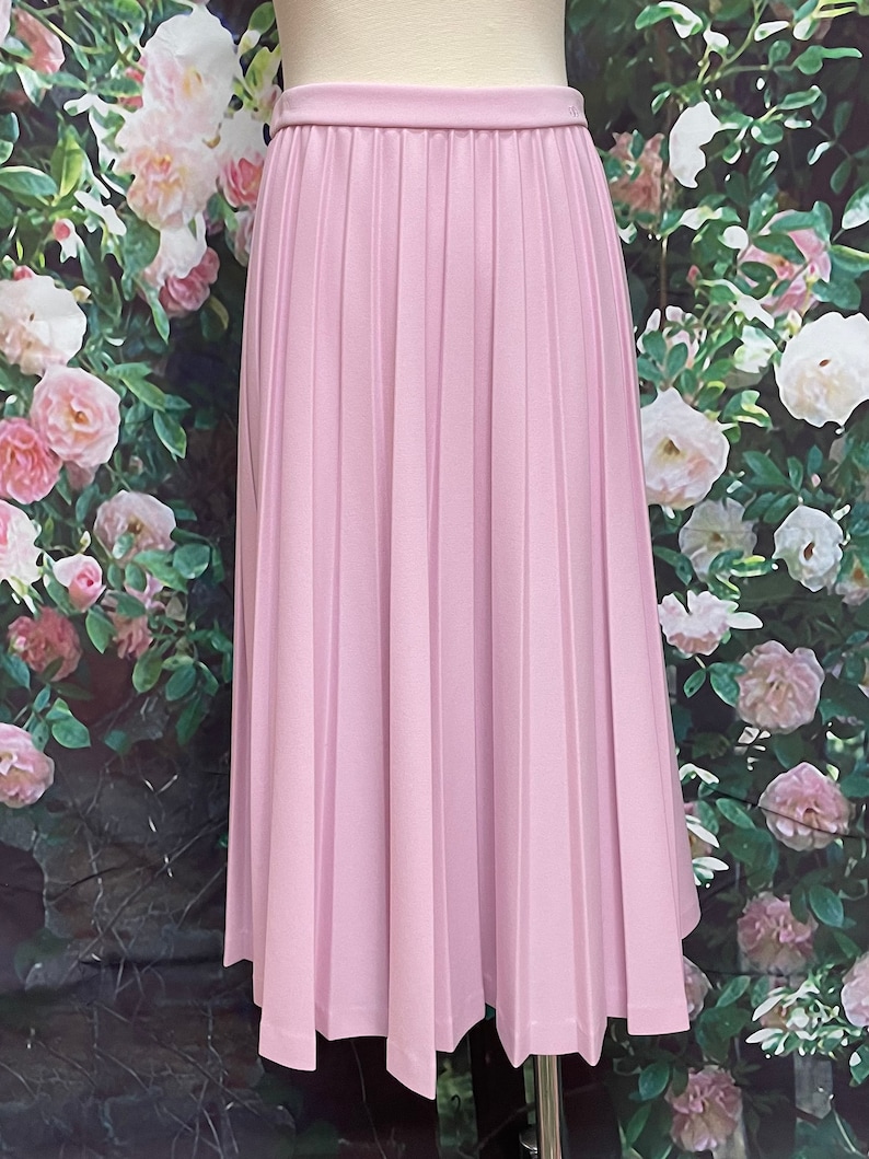 May include: A light purple pleated skirt with a straight hemline. The skirt is made of a smooth, lightweight fabric.