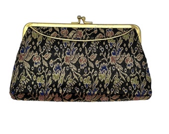 May include: A black and gold floral patterned clutch purse with a gold metal clasp.