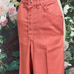 May include: A pair of wide-leg pants in a coral pink color. The pants have a high waist and a straight leg.