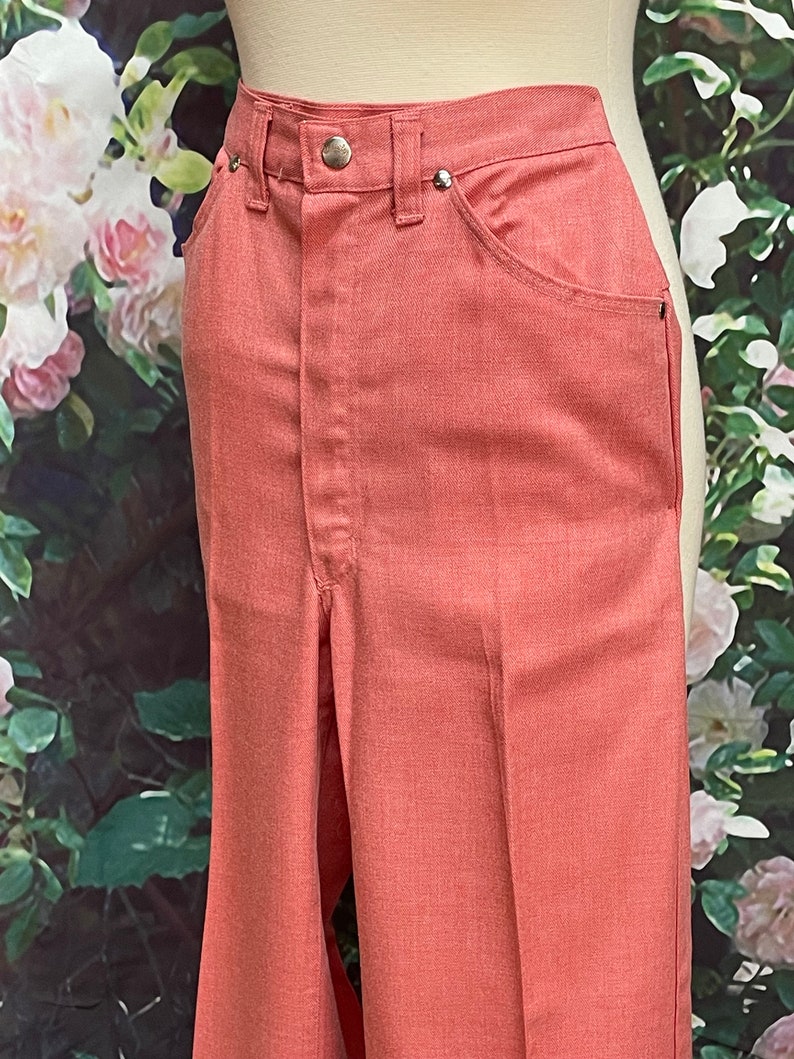 May include: A pair of wide-leg pants in a coral pink color. The pants have a high waist and a straight leg.