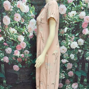 May include: A pink midi dress with a floral print. The dress has a V-neckline, short sleeves, and a button-up front.