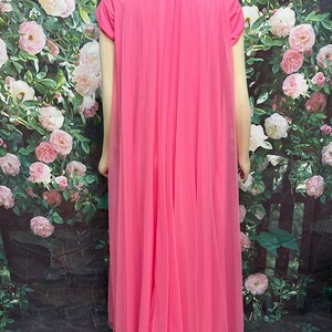 May include: A floor-length, bright pink nightgown featuring a solid-colored base layer with short sleeves and a sheer, flowing chiffon overlay that drapes from the shoulders to the hem, creating a layered, pleated appearance throughout the garment.