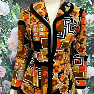May include: A black, orange, and brown patterned jacket with a black velvet collar and trim. The jacket has a button closure and a fitted silhouette.