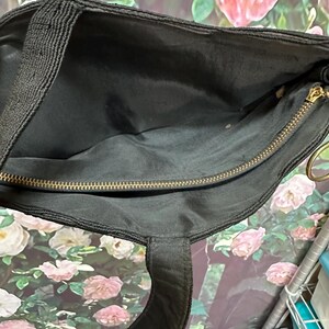 May include: Black corduroy tote bag with a gold zipper and a black strap. The bag is open and the inside is visible.