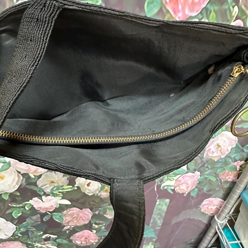 May include: Black corduroy tote bag with a gold zipper and a black strap. The bag is open and the inside is visible.