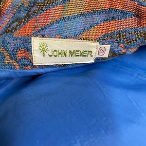 May include: A close-up of a blue and orange patterned fabric with a white tag that reads "JOHN MEYER" and a size 12 tag.