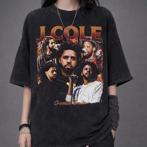 May include: Black t-shirt with a collage of J. Cole images, the text "J. Cole" in orange, and "Crooked Smile" in red. The shirt has a vintage, distressed appearance.